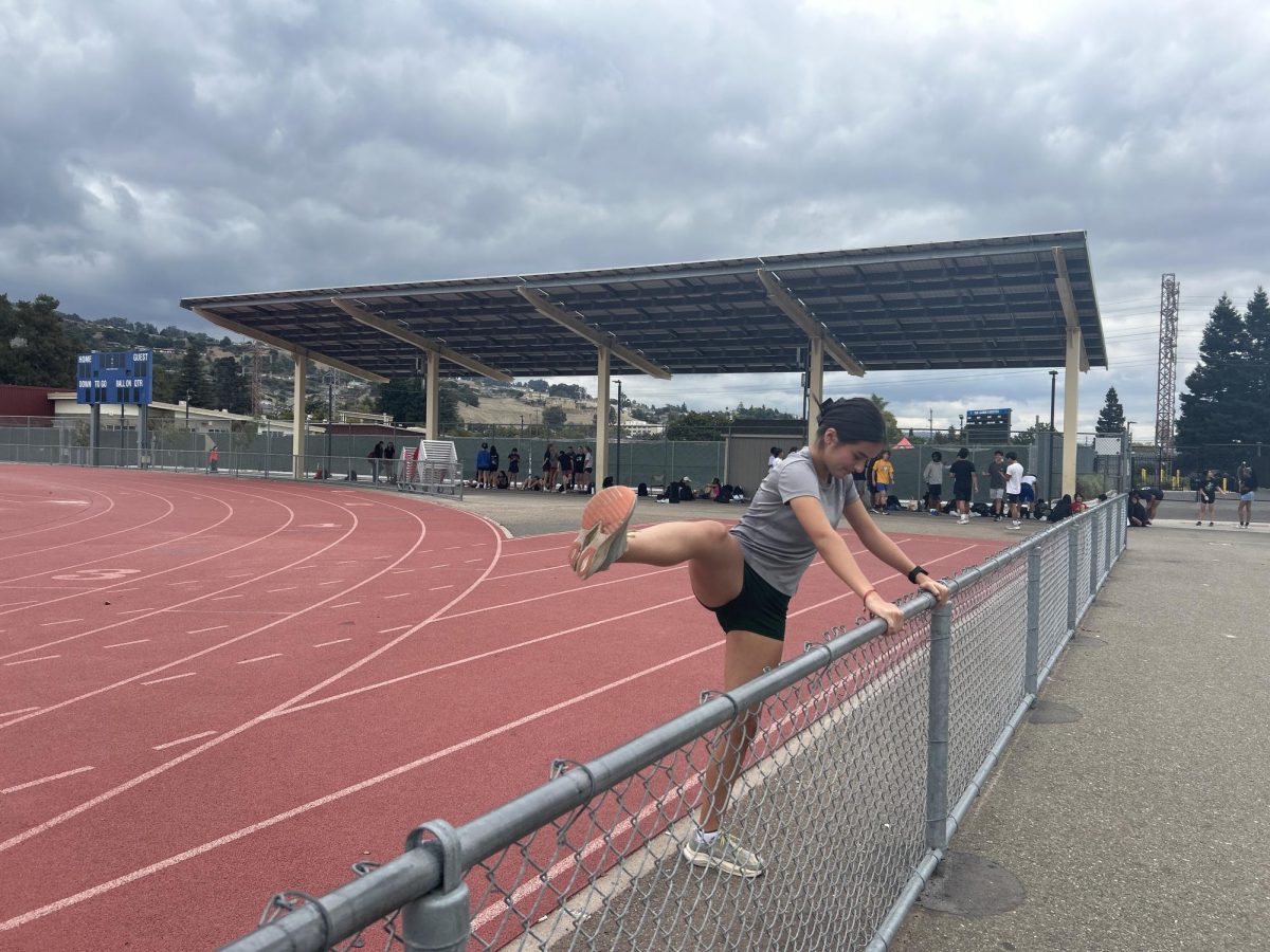 Girls varsity cross country runner Xena Leon warms up as teammates are arriving to practice. 